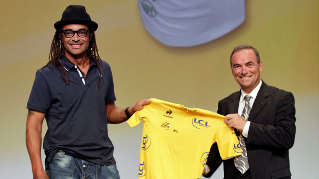 Yannick Noah (L) and five-time Tour de France champion Bernard Hinault present the new Yellow jersey during the official presentation of 2012 Tour de France (Getty)