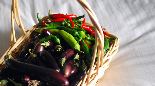 a basket filled with chillis and eggplants