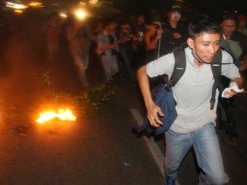 Protesters run from riot police during a protest against the government's plan to raise fuel prices outside the parliament in Jakarta, Indonesia. (AAP)