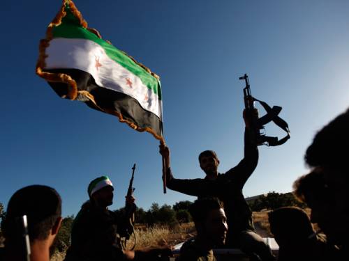 A Free Syrian Army member holds a weapon and a Syrian revolutionary flag during a training session on the outskirts of Idlib, Syria. (AAP)