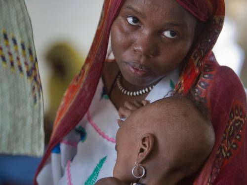 A child, suffering from malnutrition, is held by her mother in an intensive care tent in the desert village of N'Gouri in the Sahel region of Africa. (AAP)