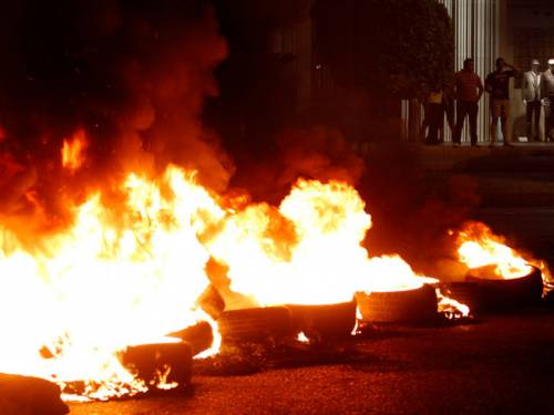 Burning tires block a road next to a clothing store during a protest after a deadly car bomb attack targeting Wissam al-Hassan, the intelligence chief of Lebanon's domestic security forces. (AAP)