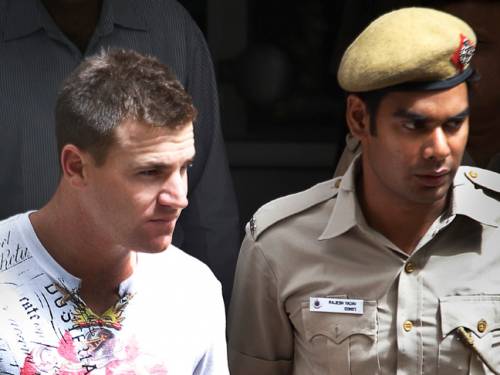 Australian cricketer Luke Pomersbach is escorted by an Indian policeman. (AAP)