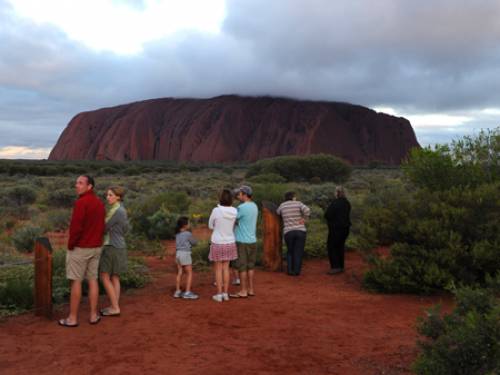 Tourists gather at the sunset carpark at Uluru on sunset ahead of celebrations for the 25th anniversary of the handback of Uluru to its traditional owners (AAP)