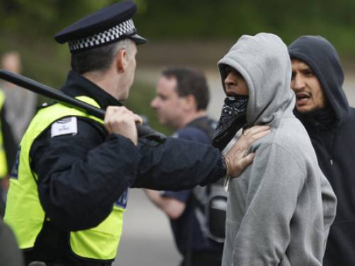 A British police officer tries to control muslim youths as they charge against badly outnumbered anti-Muslim protesters (AAP)