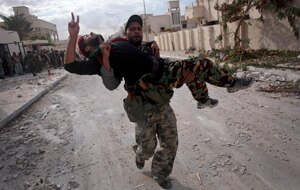 A Libyan anti-Gaddafi fighter carries a mate in Sirte. (AAP)